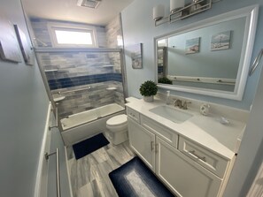 Bathroom features a glass-enclosed shower, bench, and a sink with a mirror.