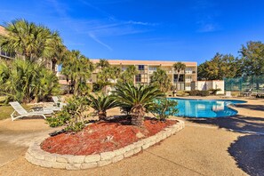 A hotel with a swimming pool, palm trees, and lounge chairs. - Biloxi Condo w/ Pool Access - Steps to Beach! (Biloxi)