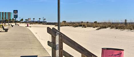 A beachside walkway with a wooden fence and a parking sign.