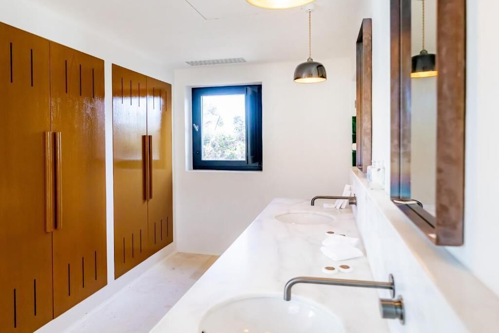 Un baño moderno con dos lavamanos, muebles de madera y una ventana.