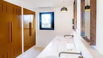 Un baño moderno con dos lavamanos, muebles de madera y una ventana.