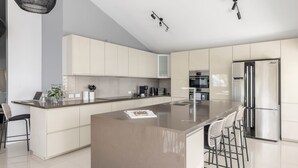 A modern kitchen with a large island, stainless steel appliances, and a minimalist design. - Tree Tops Water Front Soldiers Point- First Floor (Soldiers Point)