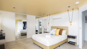 A modern bedroom with a large bed, bedside tables, a mirror, and a ceiling fan. - Tree Tops Water Front Soldiers Point- First Floor (Soldiers Point)