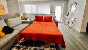 A bedroom with a bed, a sofa, a small table, and a mirror on the wall. - King Bed, 3 miles to Stadium (Miami Gardens)