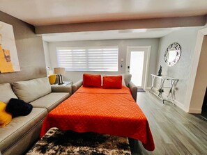 A bedroom with a bed, a sofa, a small table, and a mirror on the wall. - King Bed, 3 miles to Stadium (Miami Gardens)