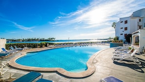 A swimming pool with lounge chairs, a clear blue sky, and a view of the sea. - Blue Bay flat with swimming pool in Alcudia Beach (Alcúdia)