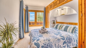 A bedroom with a bed, a window with curtains, a plant, and a view of the outdoors. - Blue Bay flat with swimming pool in Alcudia Beach (Alcúdia)