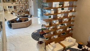 Amplia sala de estar con un sofá curvo, una estantería de madera con adornos y un piso de mármol.