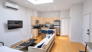 Un apartament modern amb saló, zona de menjador, cuina i un dormitori.