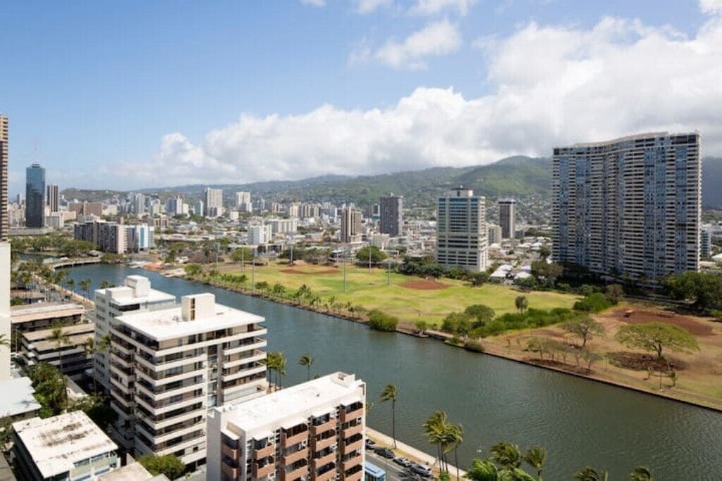 A cityscape with modern high-rise buildings, a river, and a park area.