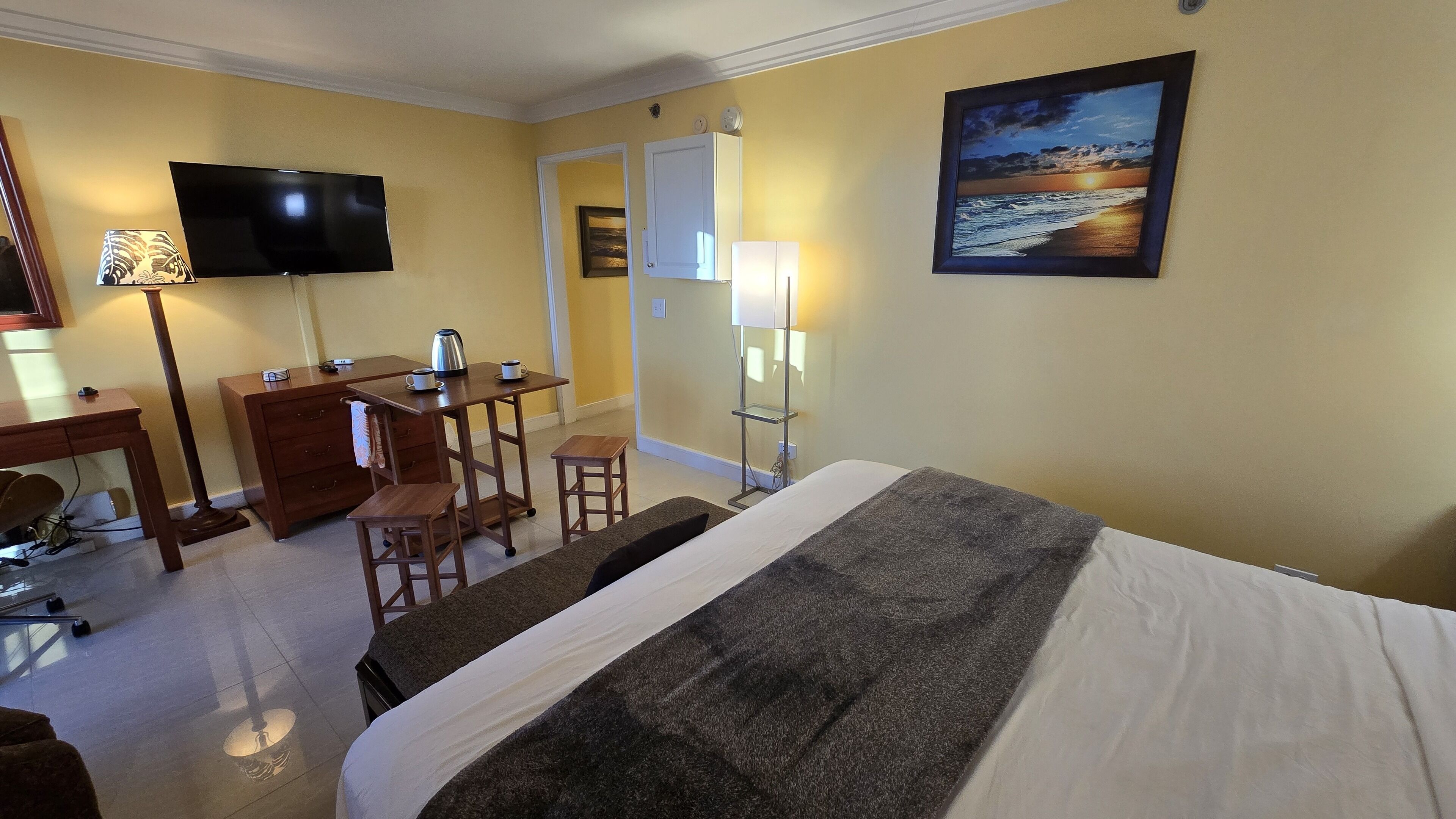 Ein Hotelzimmer mit Bett, Schreibtisch, Stühlen, Fernseher und einem Bild an der Wand.