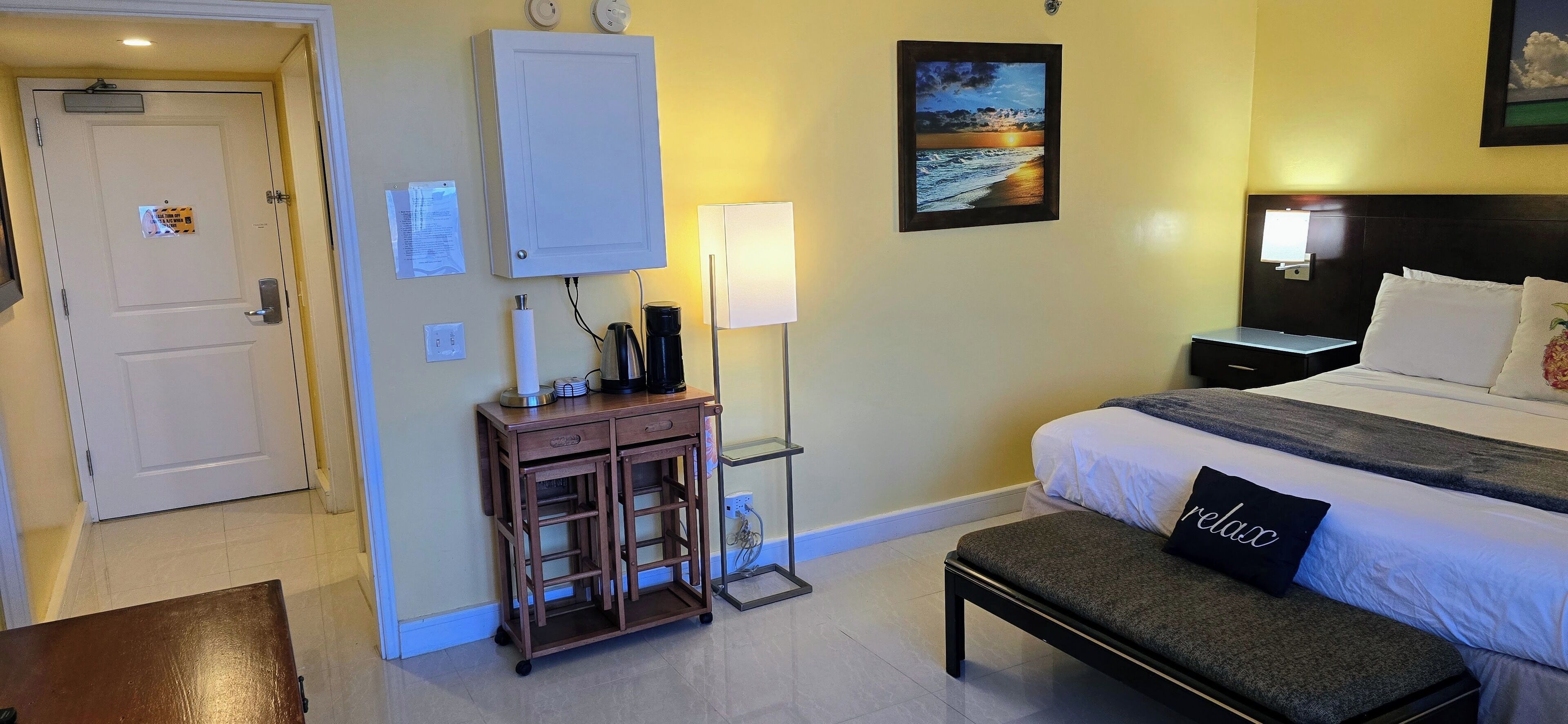 A hotel room with a bed, bedside table, lamp, and a wall-mounted cabinet.