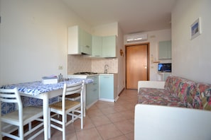 A compact kitchen with a dining table, chairs, a sofa, and a television. - Choose to Spend Your Holiday With Beahost Rentals! (San Michele al Tagliamento)