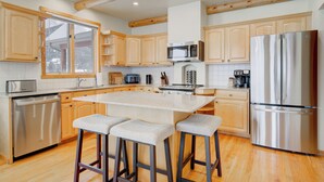 A modern kitchen with wooden cabinets, stainless steel appliances, and a central island with bar stools.