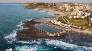 An aerial view of Newcastle Beach and Ocean Baths with a large pool, promenade, and residential buildings.
