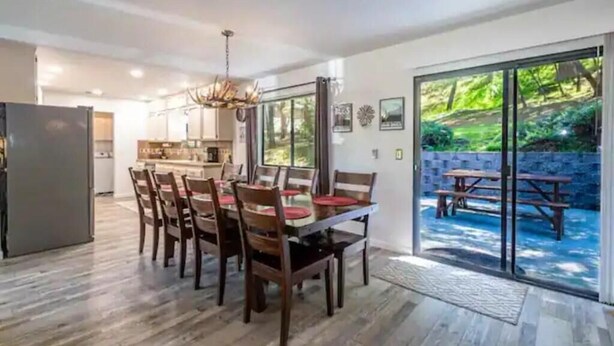 Un coin repas avec une table et des chaises, une cuisine en arrière-plan et une vue sur un patio avec une piscine.