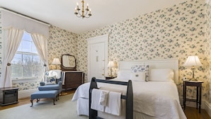 A bedroom with floral wallpaper, a four-poster bed, a dresser, a vanity with a mirror, and two bedside lamps. - Peaceful Maine B&B Room  Cozy Stay + Farm-Fresh Breakfast Room 5 (Limerick)