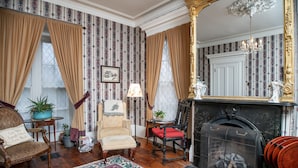 A traditional room with patterned wallpaper, a fireplace, a mirror, and classic furniture. - Peaceful Maine B&B Room  Cozy Stay + Farm-Fresh Breakfast Room 5 (Limerick)