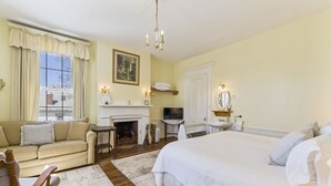 A hotel room with a large bed, a sofa, a fireplace, a television, and a bathroom.