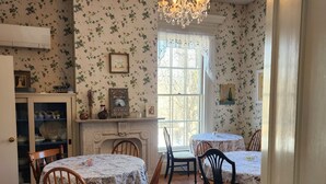 A dining room with a chandelier, floral wallpaper, and a fireplace.