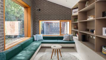 A modern interior with a green sofa, a white round table, and a brick wall.
