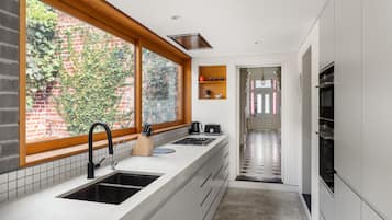 A modern kitchen with a large window, a built-in oven, and a stainless steel sink.