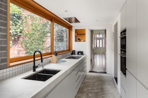 A modern kitchen with a large window, a built-in oven, and a stainless steel sink.