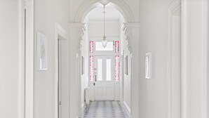 Un couloir avec un sol à motifs, des murs blancs et une porte au fond.