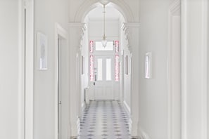 A hallway with a patterned floor, white walls, and a door at the end. - The Atrium Abbotsford House BBQ and Parking (Abbotsford)