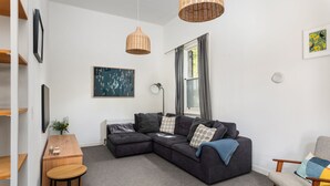 Un salon moderne avec un canapé d’angle, une petite table en bois et un fauteuil.