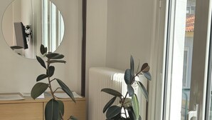 A room with a wooden desk, a potted plant, a mirror, and a radiator.