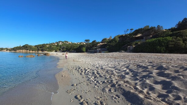A beach with clear water, footprints, and buildings in the background. - Appartement T1 bis Accès Plage à 50m - Rupione (Pietrosella)
