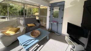 A modern living room with a sofa, a coffee table, a TV, and a door with a unique design. - Appartement T1 bis Accès Plage à 50m - Rupione (Pietrosella)