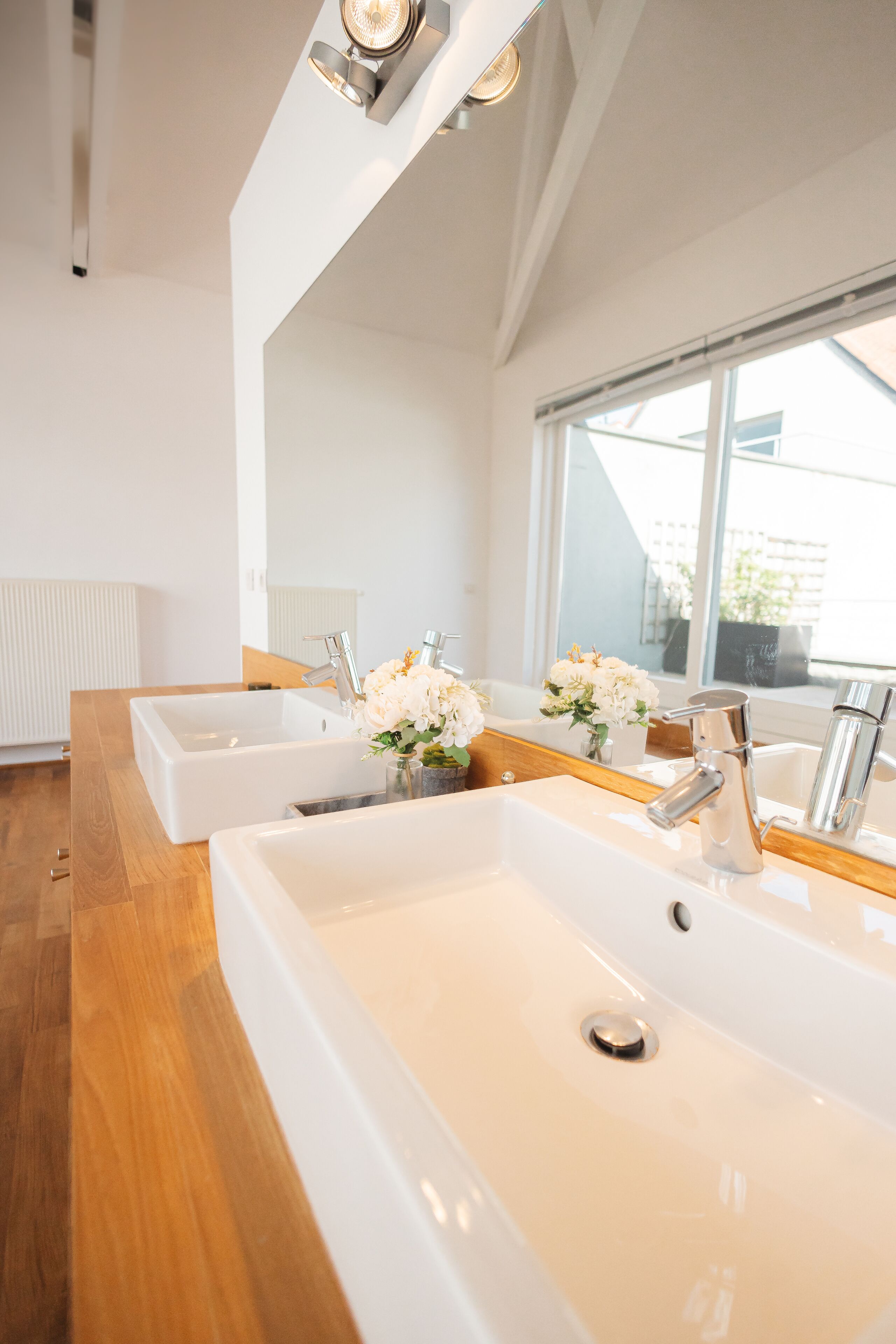 Une salle de bain moderne avec deux lavabos, un meuble-lavabo en bois et un grand miroir.