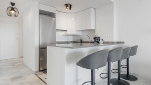 A modern kitchen with a central island, bar stools, and a built-in oven.