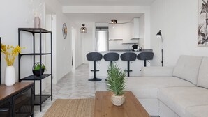 A modern living room with a sofa, a coffee table, and a kitchen in the background.
