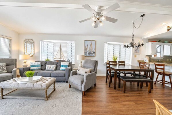 Una sala moderna con un sofá gris, una mesita de centro y un comedor con muebles de madera.