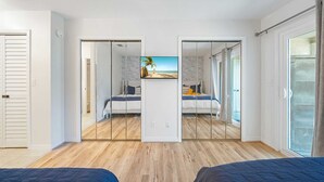 A bedroom with a large mirror, a bed, and a view of the beach through the window. - 4819B Stunning Townhouse - 2 bed/2.5 bath Pet Friendly! (Panama City Beach)