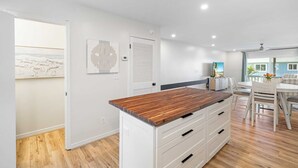 A modern kitchen with a wooden countertop, white cabinets, and a view to the dining area. - 4819B Stunning Townhouse - 2 bed/2.5 bath Pet Friendly! (Panama City Beach)