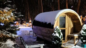 A snow-covered outdoor area with a wooden cabin and a covered seating area. - Everchanging Seasons: Charming Retreat + Cottage • Hot Tub • Sauna • Game Haven (Burnsville)