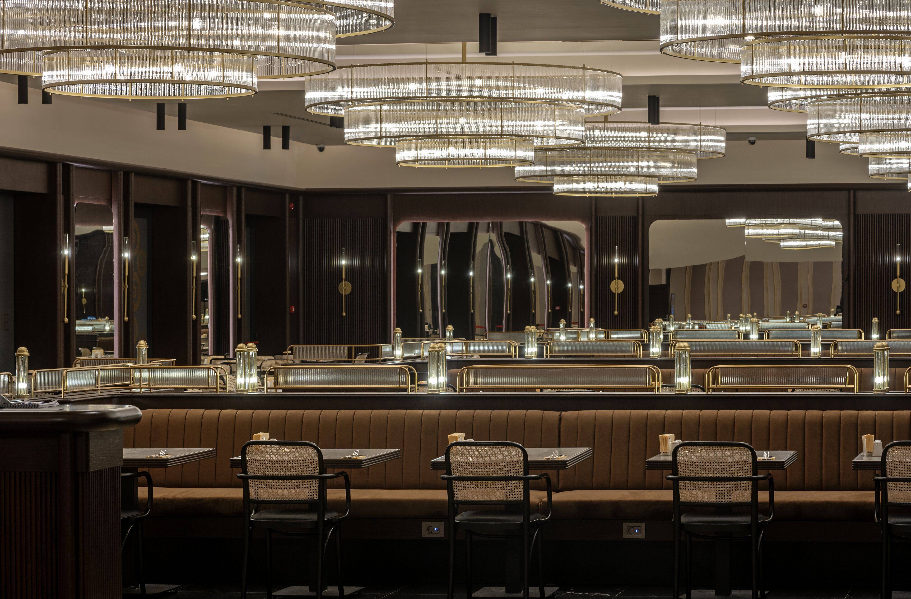 Un restaurant moderne doté de plusieurs espaces de restauration, notamment des banquettes et des tables.