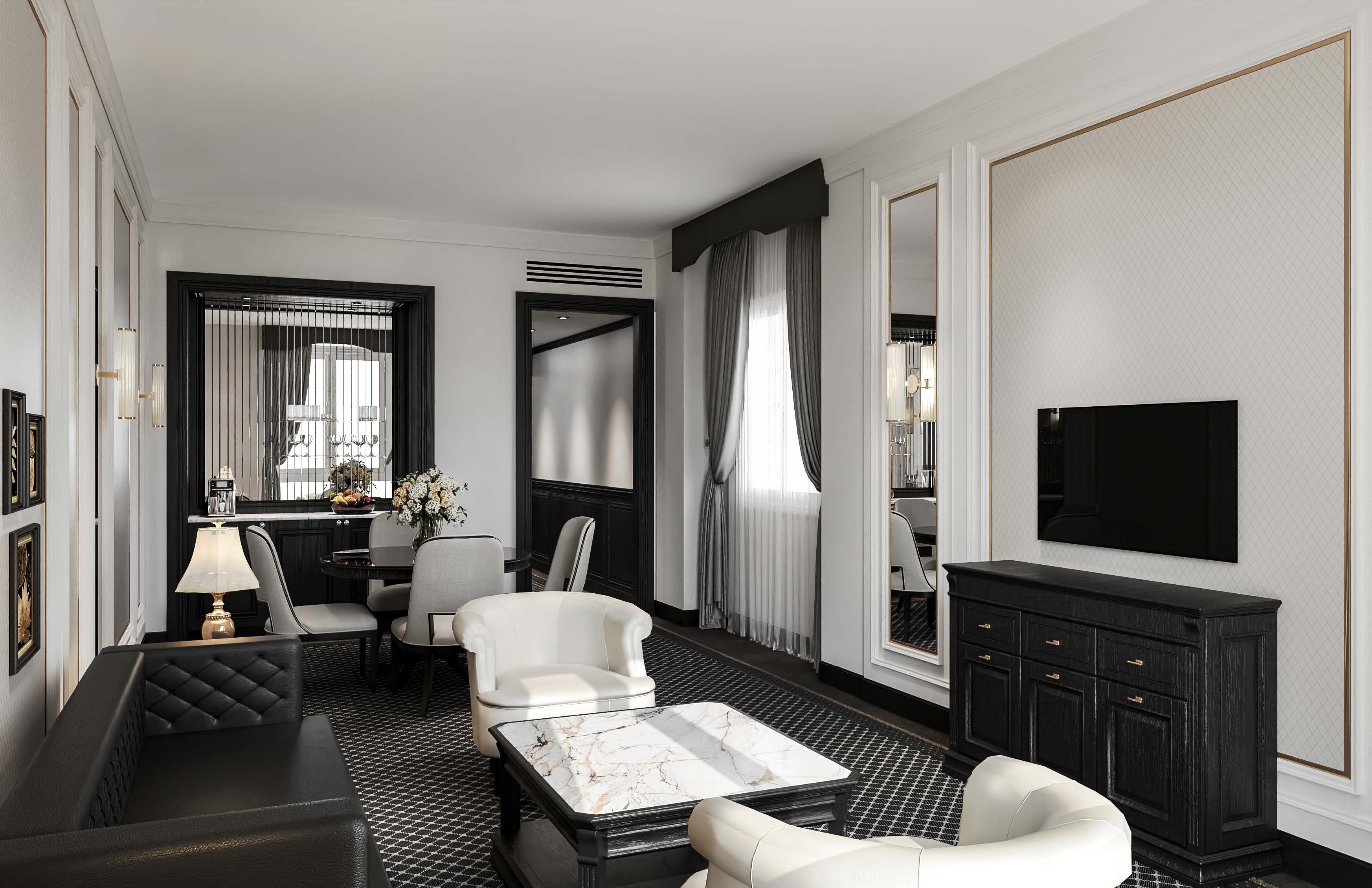 Une chambre d’hôtel moderne aux couleurs noir et blanc, comprenant un canapé, des fauteuils, une table à manger et un téléviseur.