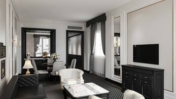 Une chambre d’hôtel moderne aux couleurs noir et blanc, comprenant un canapé, des fauteuils, une table à manger et un téléviseur.