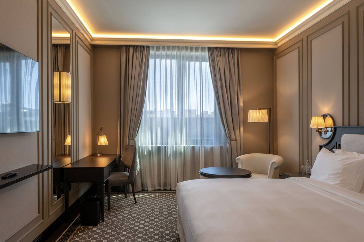 Une chambre d’hôtel équipée d’un lit, d’un bureau, d’une chaise et de deux lampes.
