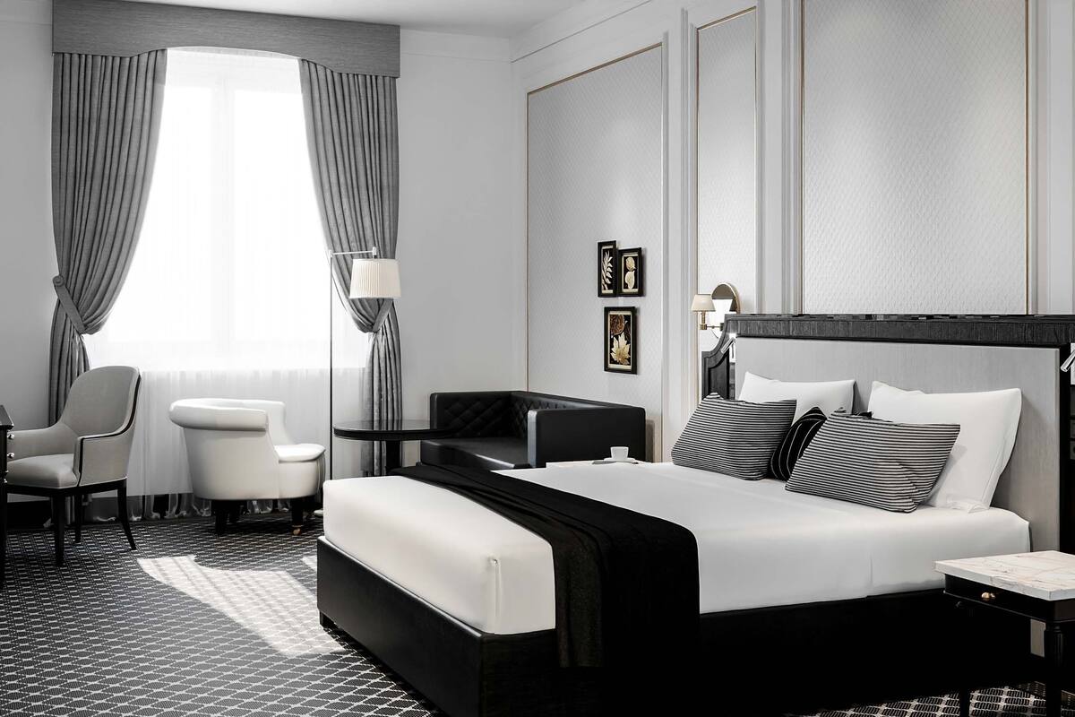 Une chambre d’hôtel moderne avec un grand lit, un bureau, une chaise et une petite table.