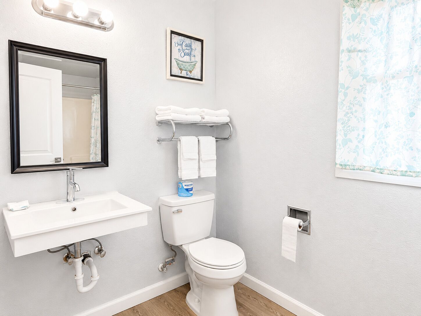 A bathroom with a white sink, a mirror, a toilet, and a towel rack.
