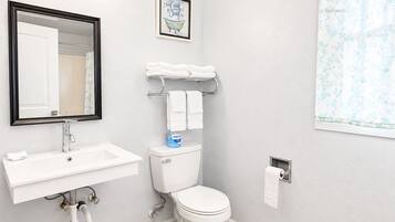 A bathroom with a white sink, a mirror, a toilet, and a towel rack.