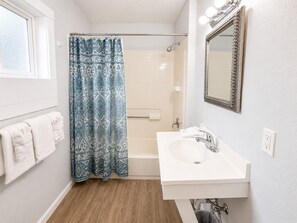 A bathroom with a shower, a sink, a mirror, and a window. - Royal Gateway Motel (Bend)