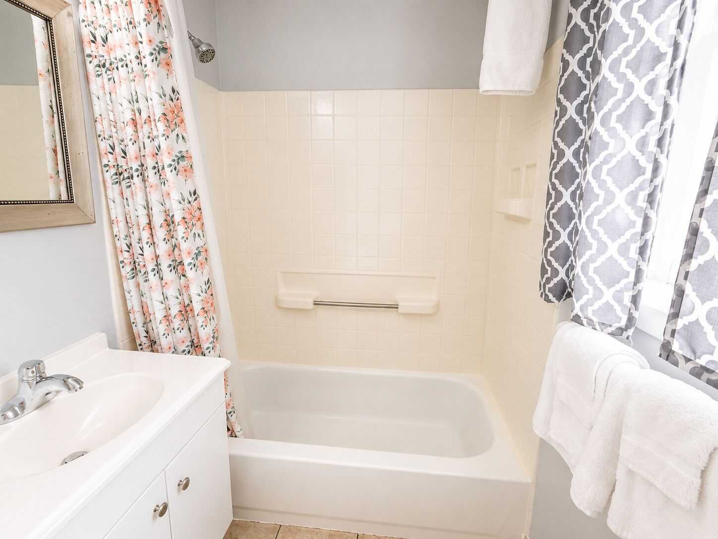 A bathroom with a white sink, a bathtub, a showerhead, and a towel rack.