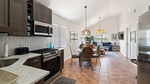 Une cuisine moderne avec des meubles de couleur sombre, un four à micro-ondes, une cuisinière et un coin repas comprenant une table ronde et des chaises.